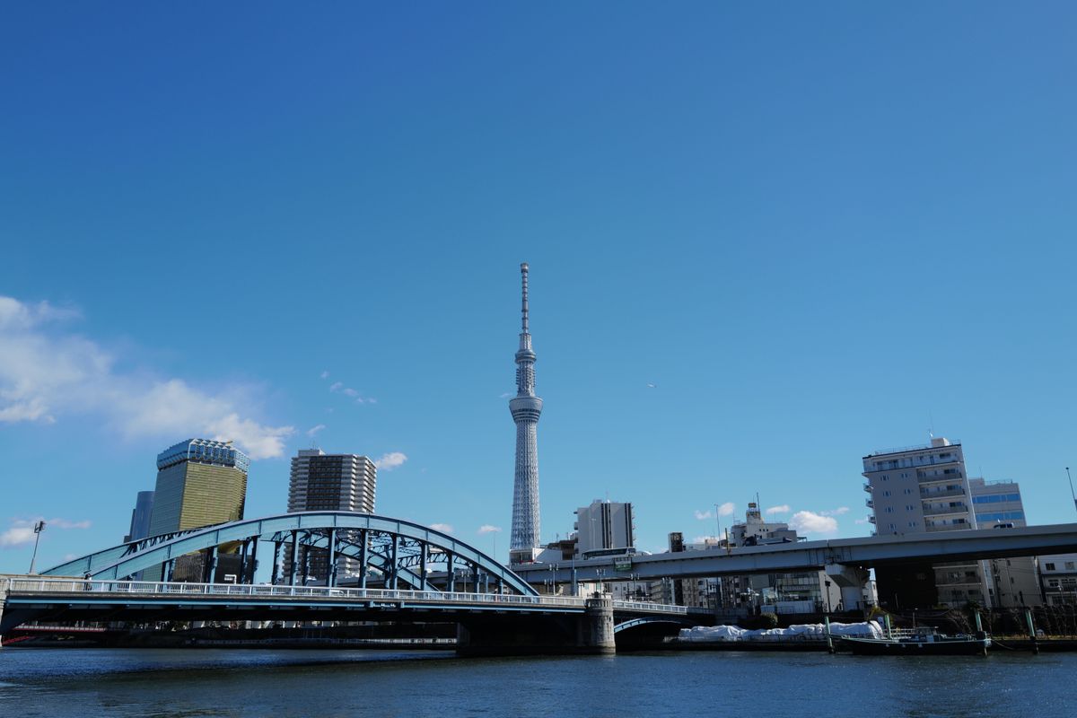 A serene view of Tokyo Skytree and Sumida River under a clear blue sky.