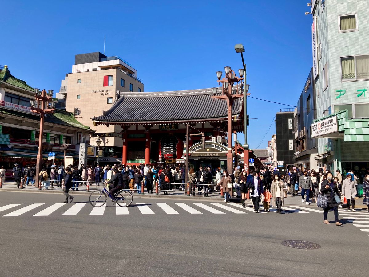 Crowds flock to the iconic Kaminarimon Gate in Asakusa, Tokyo on a sunny day, creating a vibrant street scene.